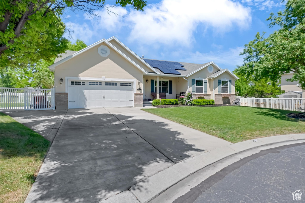 Ranch-style home featuring brick siding, a porch, roof mounted solar panels, driveway, and an attached garage