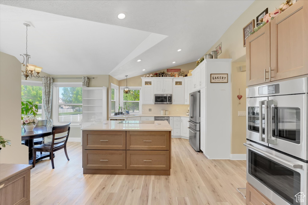 Kitchen with a chandelier, stainless steel appliances, lofted ceiling, light wood finished floors, and light countertops