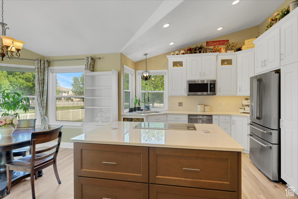 Kitchen with stainless steel appliances, vaulted ceiling, a chandelier, a sink, and healthy amount of natural light