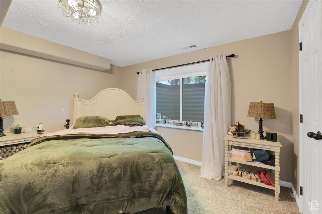 Bedroom with light colored carpet, a textured ceiling, and baseboards