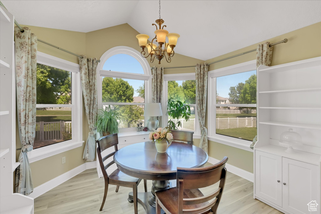 Dining space with a chandelier, vaulted ceiling, light wood-style flooring, and baseboards