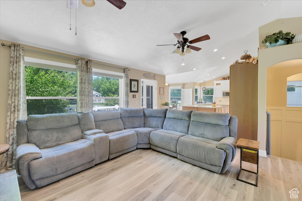 Living room featuring a ceiling fan, light wood-style floors, arched walkways, vaulted ceiling, and recessed lighting