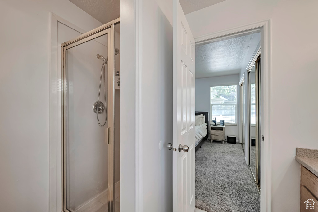 Ensuite bathroom featuring a shower stall, a textured ceiling, and vanity