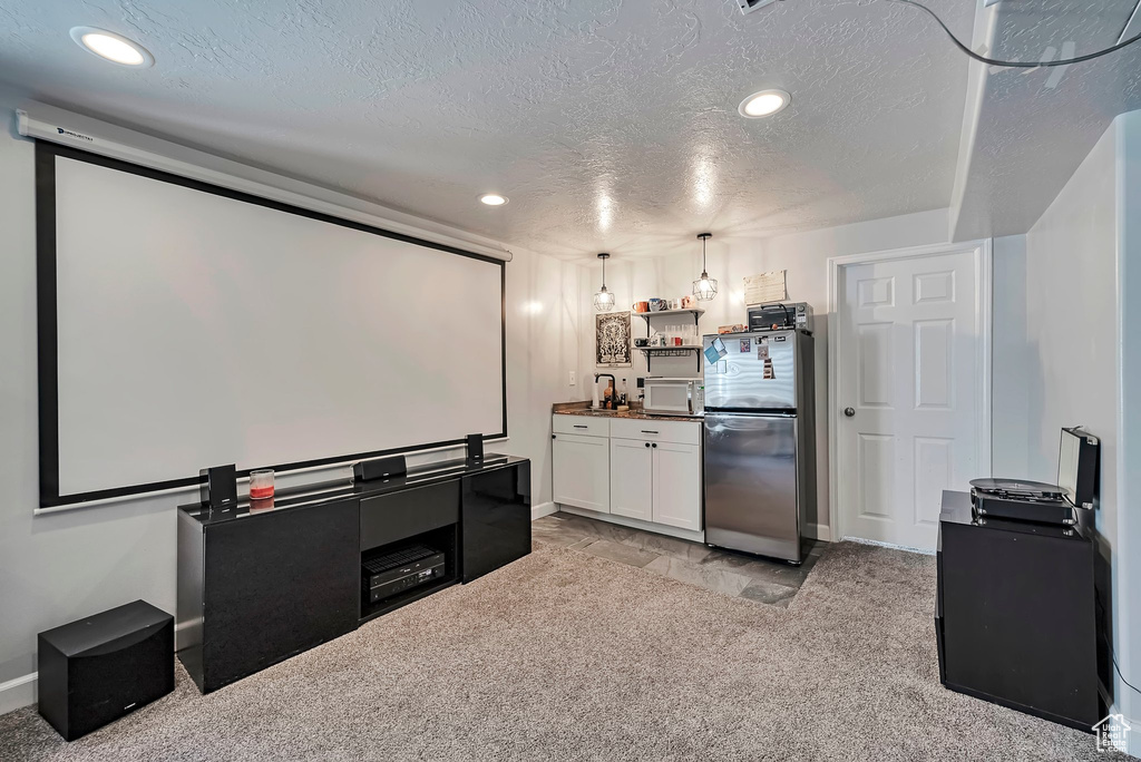Home theater featuring a textured ceiling, light carpet, recessed lighting, baseboards, and bar