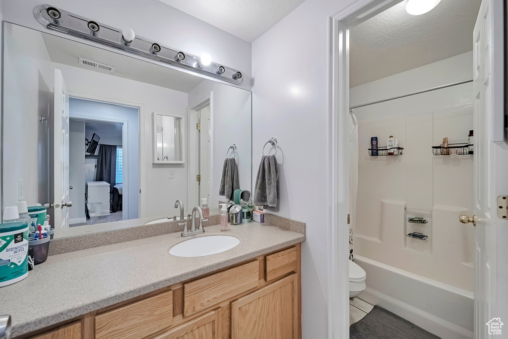Bathroom with vanity, shower / tub combo with curtain, toilet, and tile patterned floors
