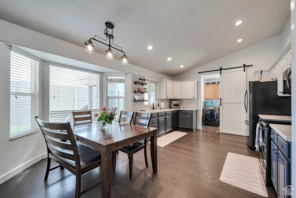 Dining room with washer / dryer, a barn door, lofted ceiling, plenty of natural light, and baseboards