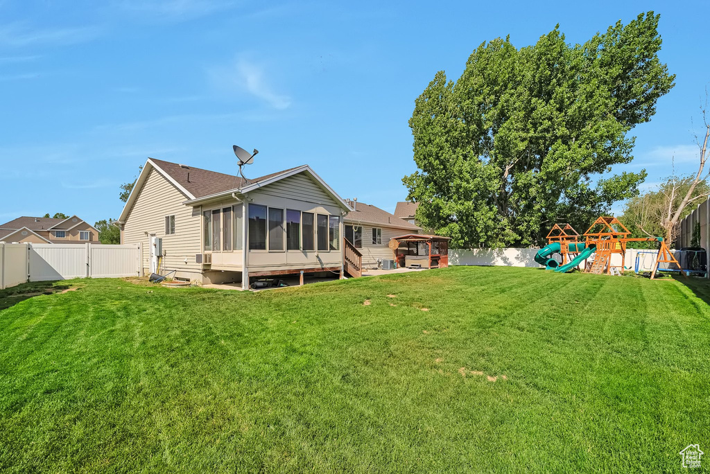 Back of house featuring a sunroom, a playground, and a gate