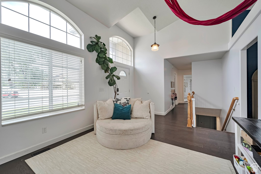 Living area with an upstairs landing, high vaulted ceiling, baseboards, and wood finished floors