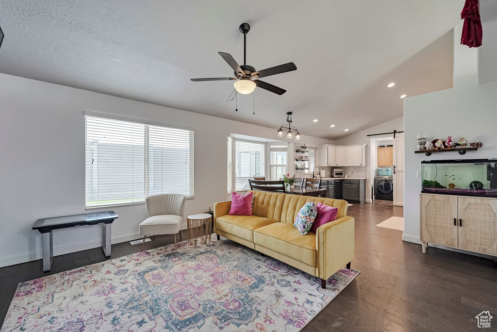 Living area with washer / clothes dryer, a barn door, ceiling fan, dark wood-style floors, and recessed lighting