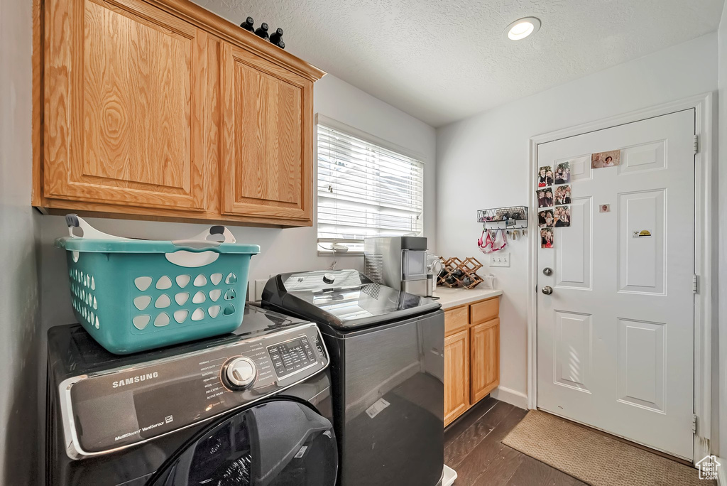 Laundry room featuring cabinet space, washer and clothes dryer, a textured ceiling, and dark wood-type flooring