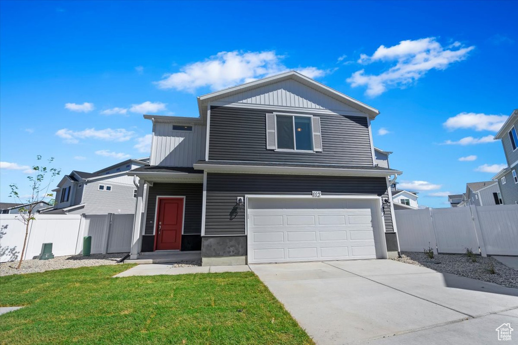 Traditional-style house with an attached garage, concrete driveway, and board and batten siding