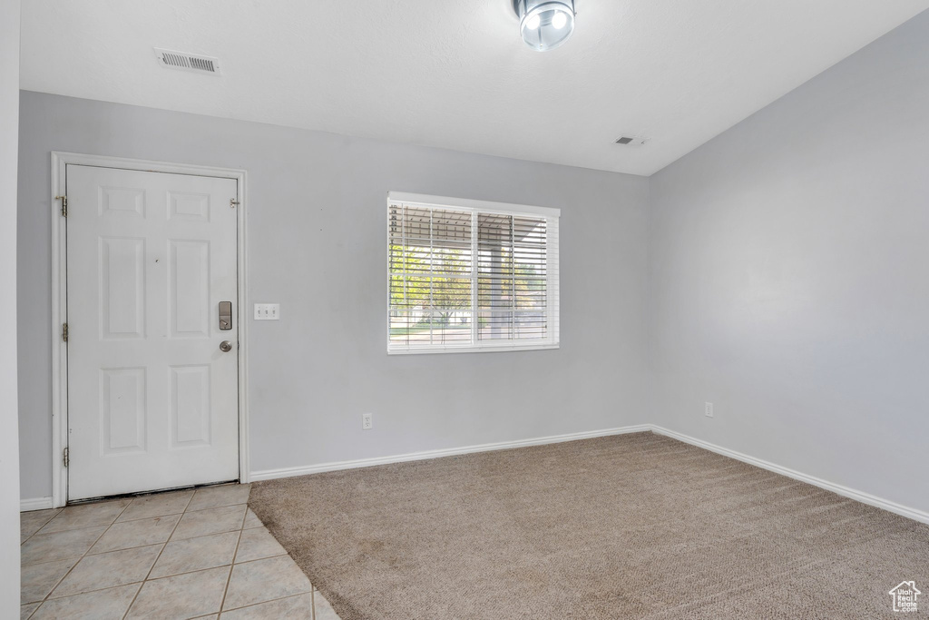 Foyer with baseboards, light tile patterned floors, and light colored carpet