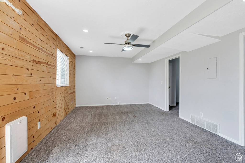 Carpeted empty room with wooden walls, a ceiling fan, recessed lighting, baseboards, and electric panel