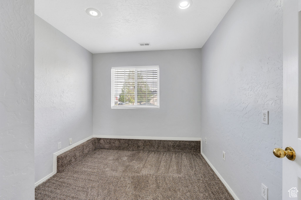 Carpeted empty room with baseboards, recessed lighting, and a textured wall
