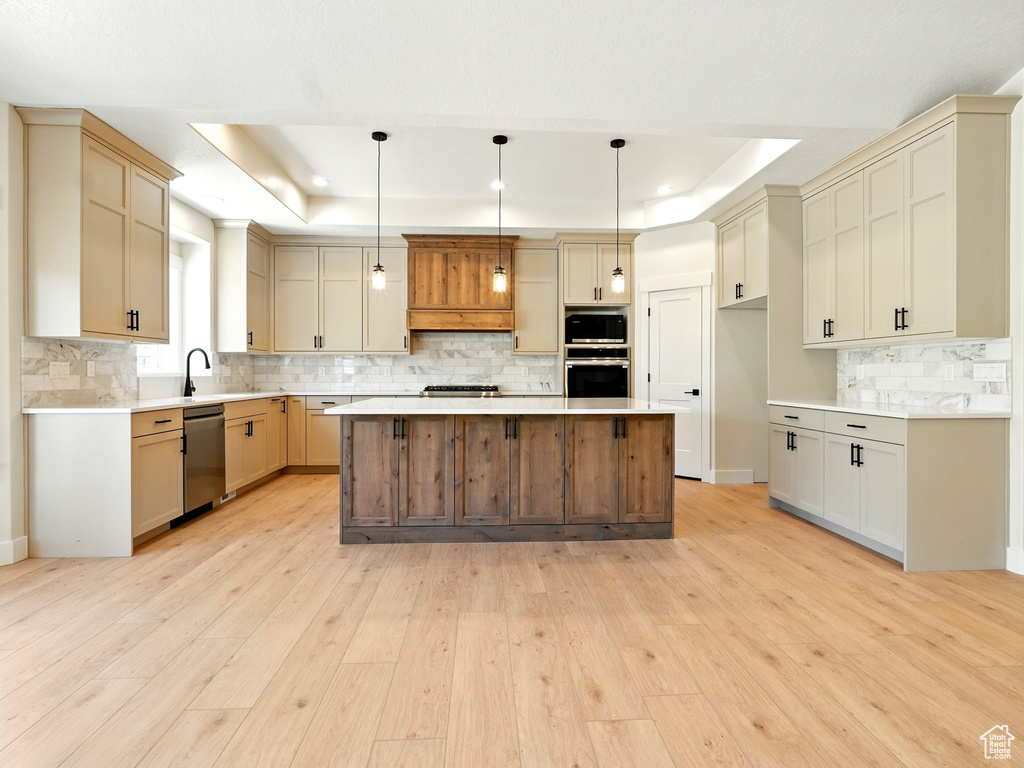 Kitchen featuring stainless steel appliances, a raised ceiling, tasteful backsplash, light wood-type flooring, and recessed lighting