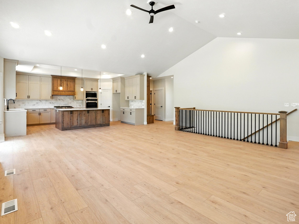 Unfurnished living room with a ceiling fan, lofted ceiling, recessed lighting, light wood-type flooring, and a sink