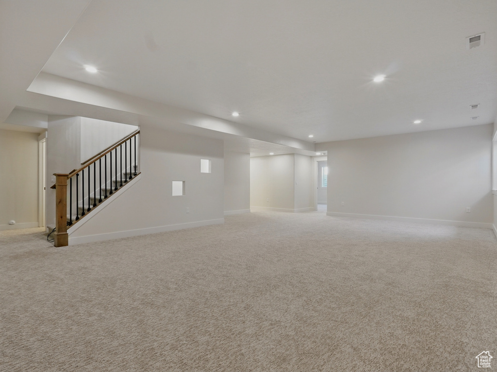 Below grade area featuring recessed lighting, stairway, light colored carpet, and baseboards