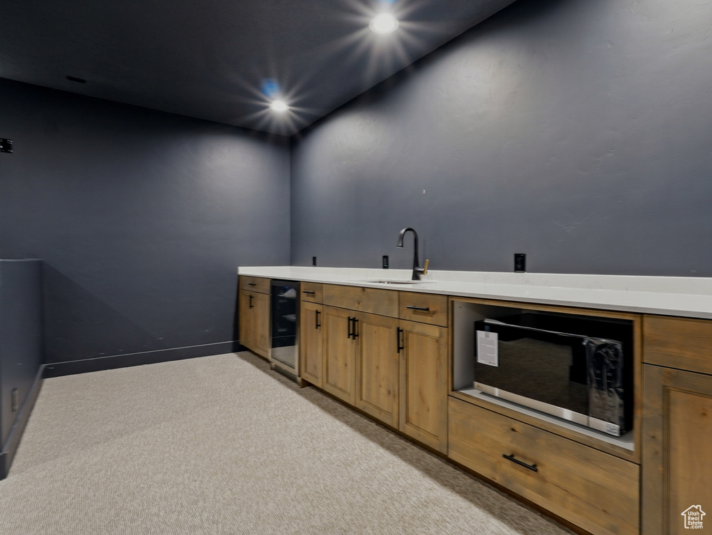 Bar with wine cooler, a sink, light colored carpet, recessed lighting, and baseboards