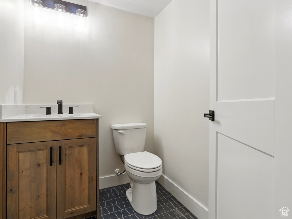 Bathroom featuring toilet, vanity, tile patterned flooring, and baseboards