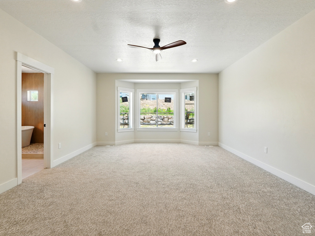 Empty room featuring light carpet, ceiling fan, baseboards, recessed lighting, and a textured ceiling