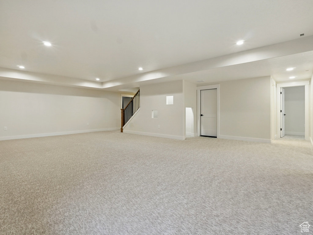 Finished below grade area with recessed lighting, light colored carpet, stairs, and baseboards