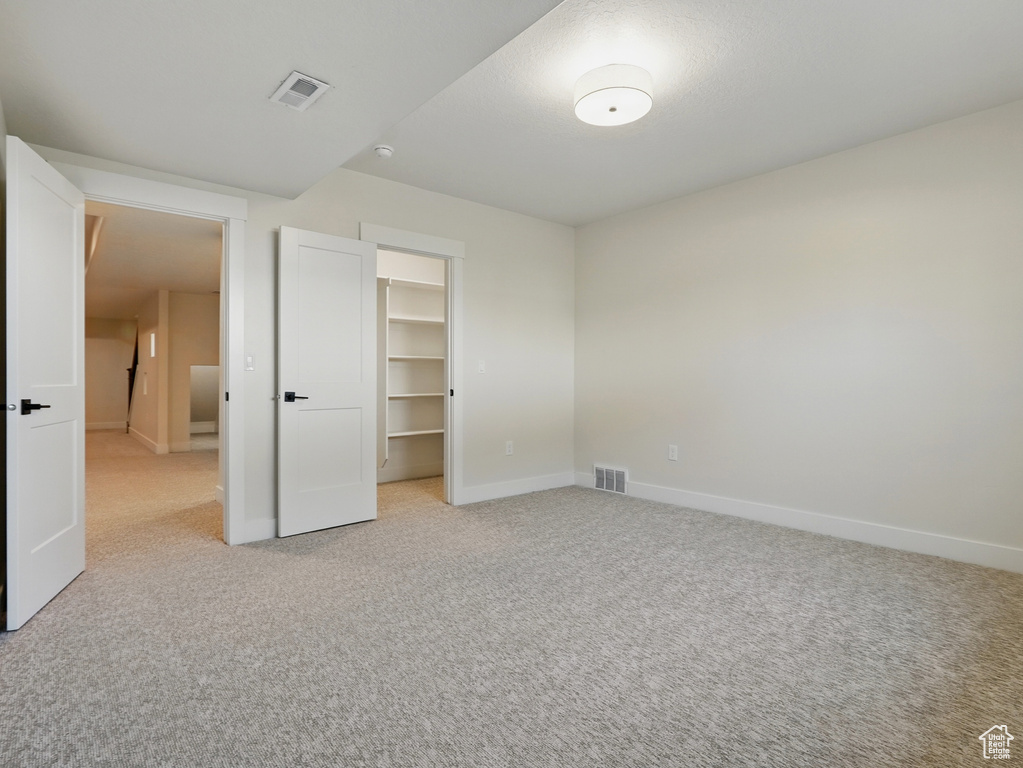 Unfurnished bedroom with light carpet, baseboards, a spacious closet, and a closet