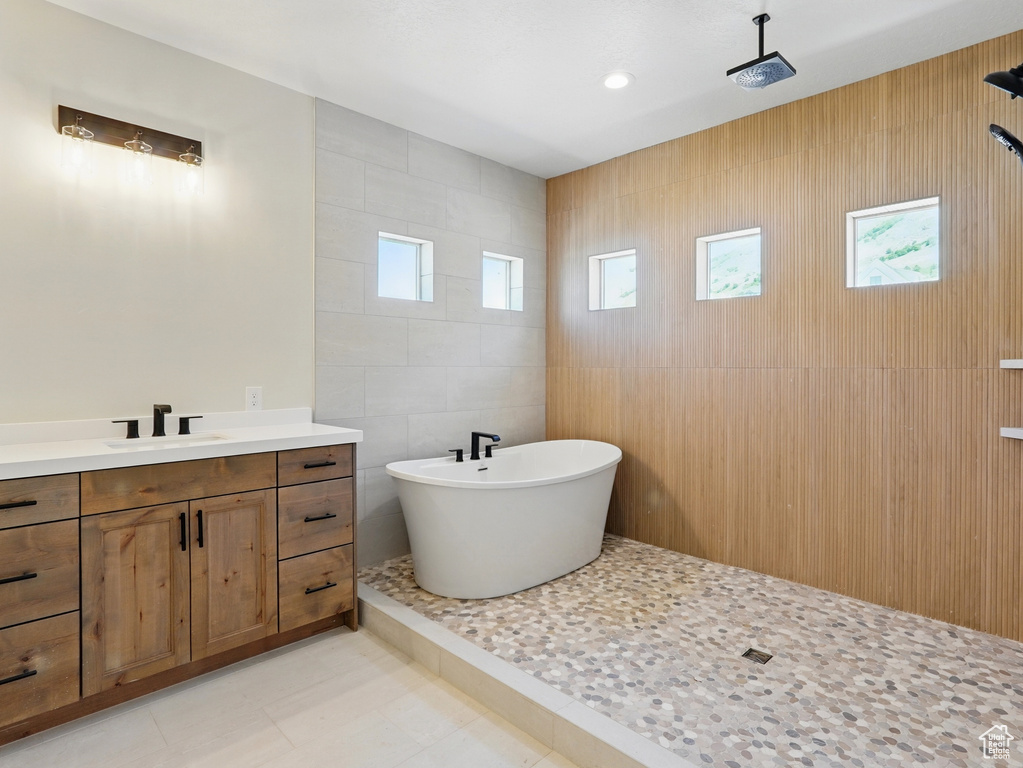 Bathroom with tile walls, a freestanding bath, healthy amount of natural light, and vanity