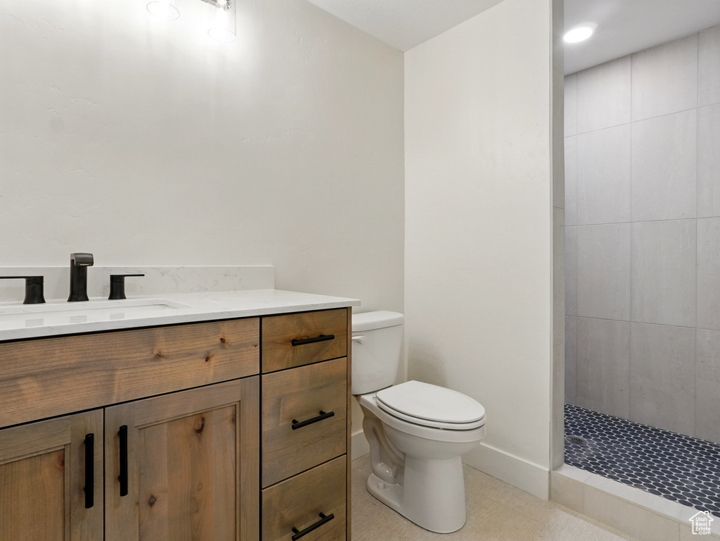 Full bathroom with toilet, vanity, a tile shower, and tile patterned floors