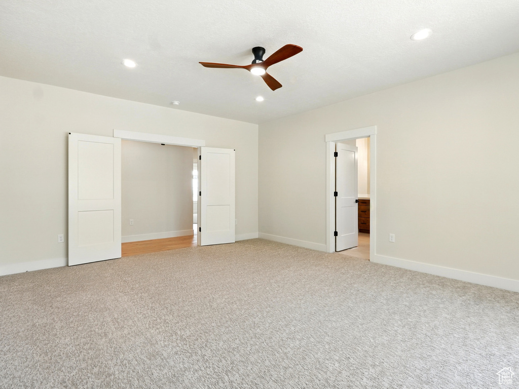 Unfurnished bedroom with light carpet, recessed lighting, baseboards, a ceiling fan, and ensuite bath