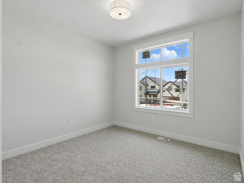 Carpeted spare room featuring baseboards