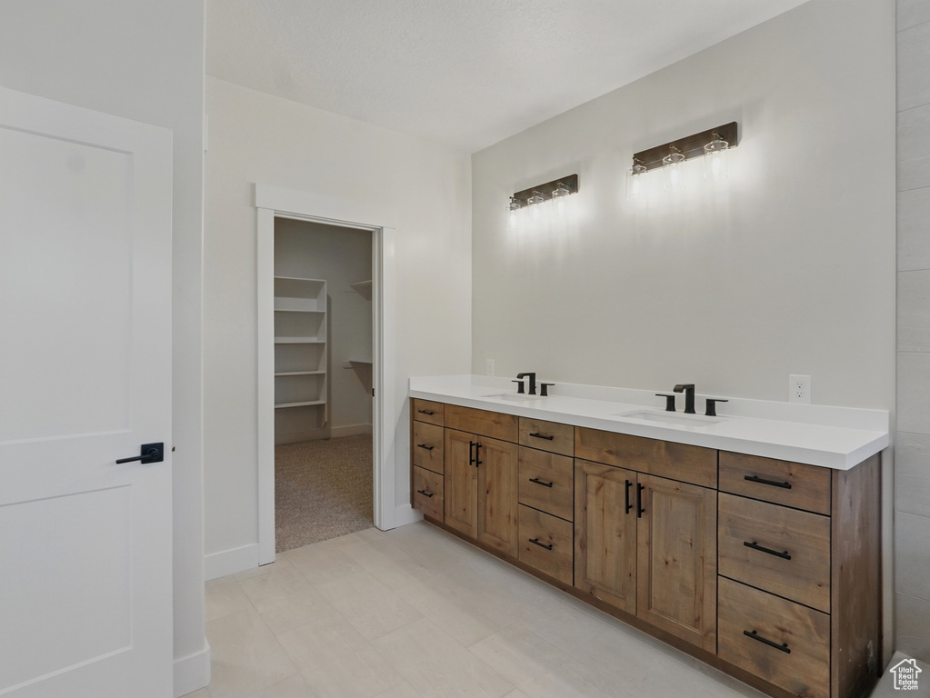 Bathroom featuring double vanity, a spacious closet, and baseboards