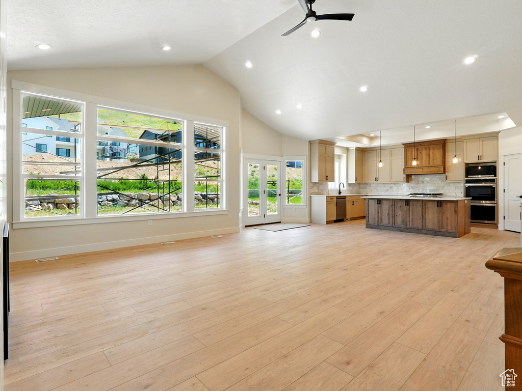 Unfurnished living room featuring a ceiling fan, french doors, a sink, high vaulted ceiling, and baseboards