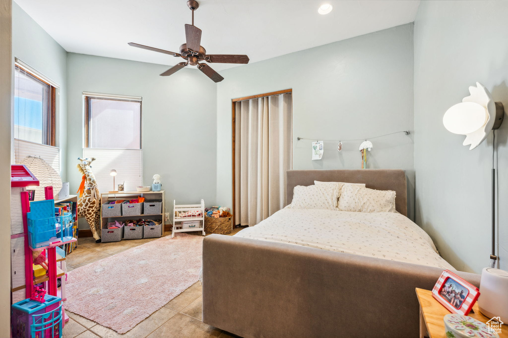 Tiled bedroom with a ceiling fan