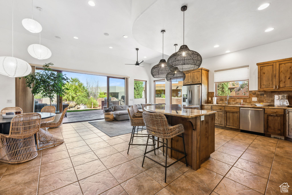 Kitchen featuring appliances with stainless steel finishes, brown cabinets, recessed lighting, decorative backsplash, and a center island