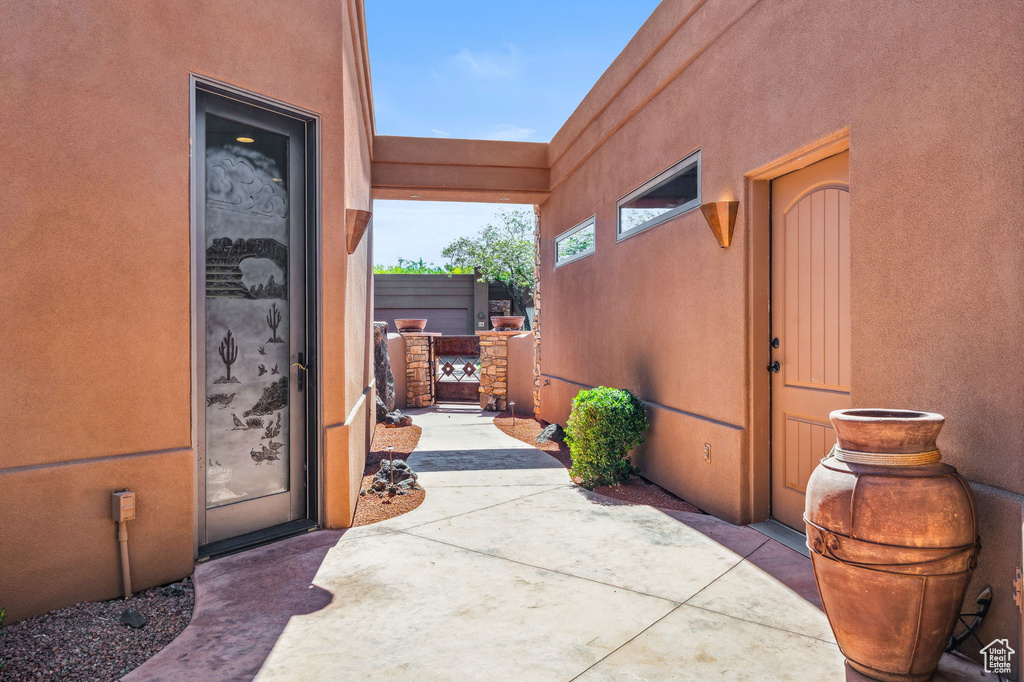 Property entrance featuring stucco siding, a gate, and a patio