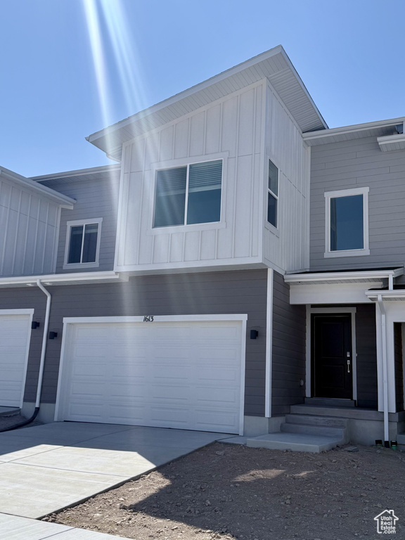 View of front facade featuring board and batten siding, an attached garage, and driveway