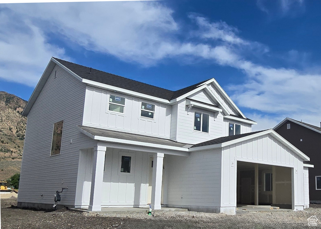 View of front facade featuring board and batten siding, covered porch, and an attached garage