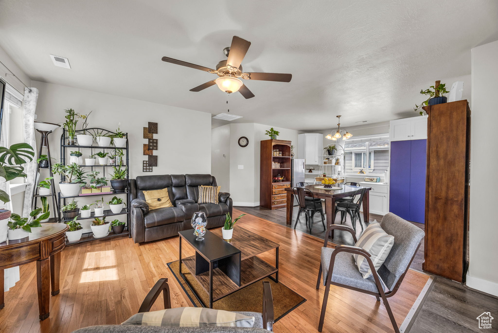 Living area with ceiling fan, light wood-style floors, a chandelier, and baseboards