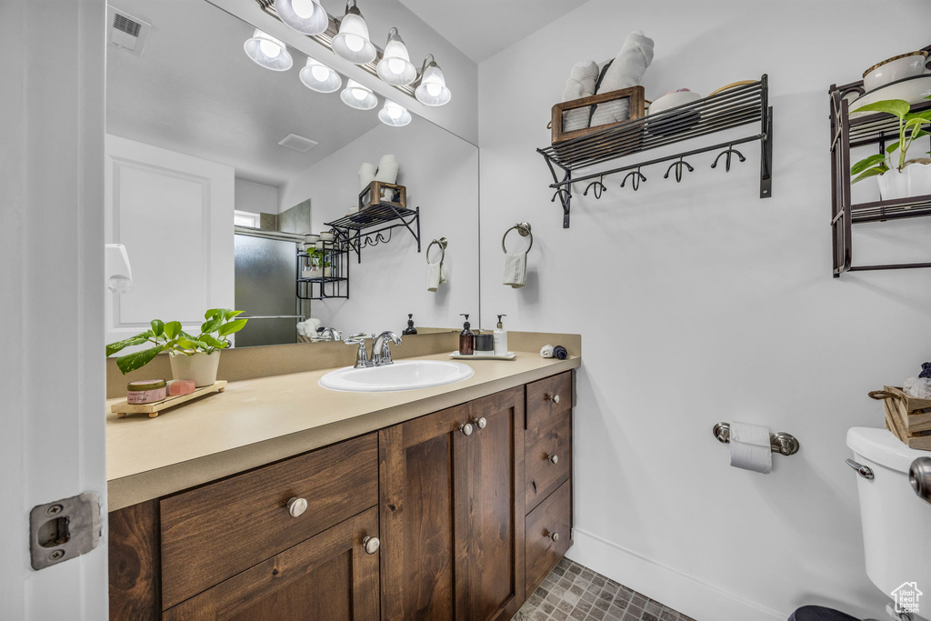 Full bath featuring vanity, toilet, a shower with shower door, and baseboards