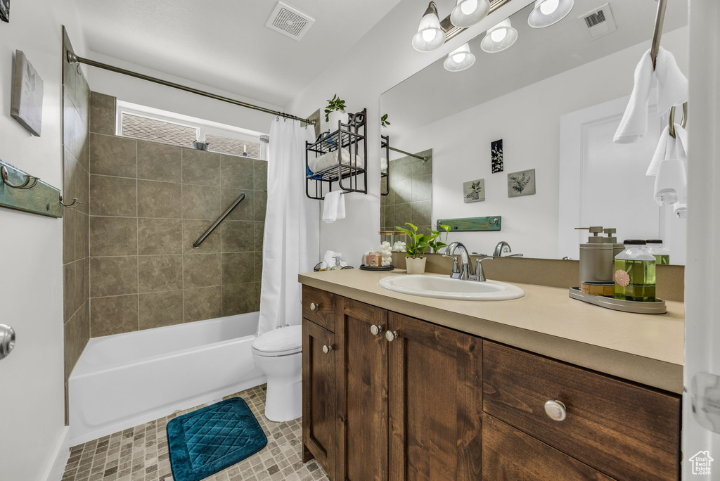 Bathroom with vanity, shower / tub combo with curtain, toilet, and tile patterned flooring