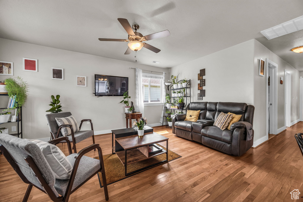 Living area featuring a ceiling fan, light wood-type flooring, and baseboards