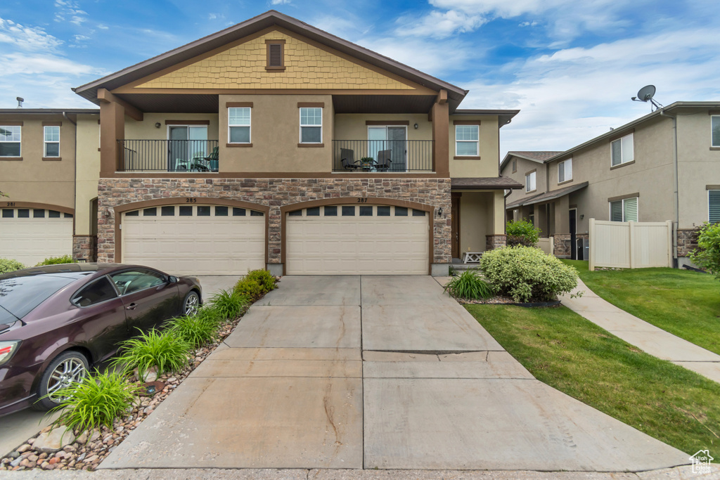 Multi unit property with stucco siding, stone siding, concrete driveway, and a garage