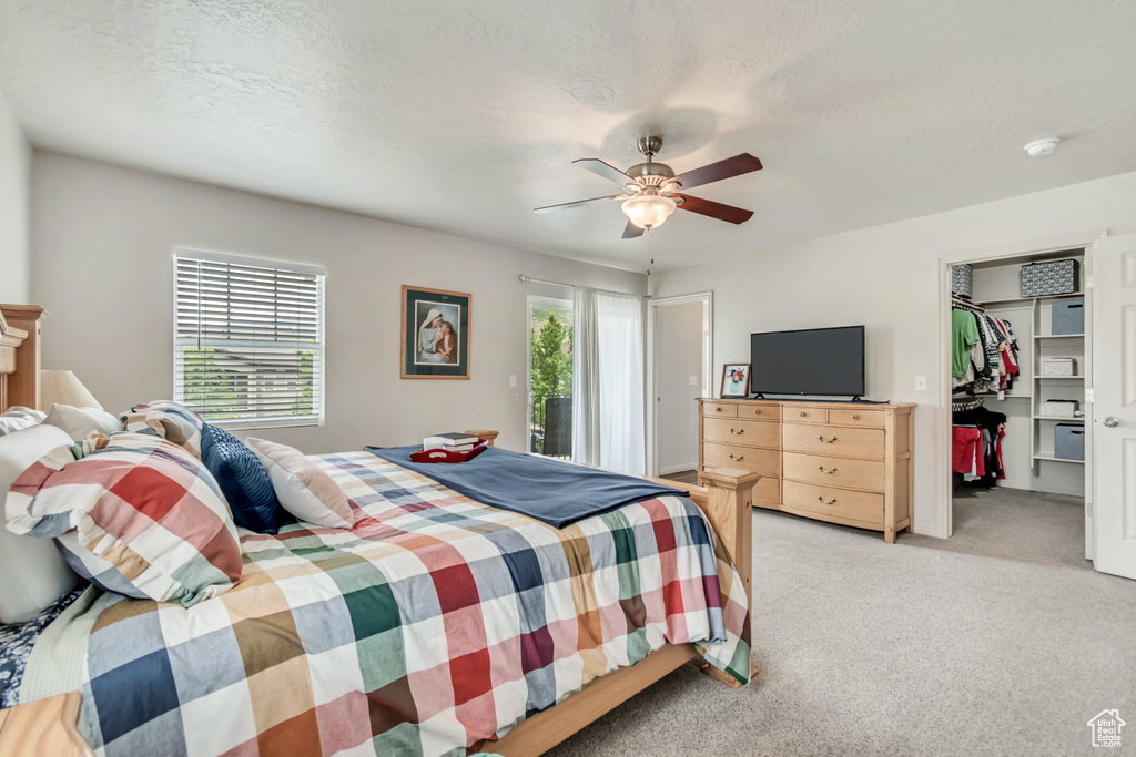 Bedroom featuring light colored carpet, ceiling fan, a spacious closet, and a closet