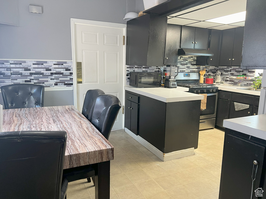 Kitchen featuring gas stove, black microwave, and backsplash