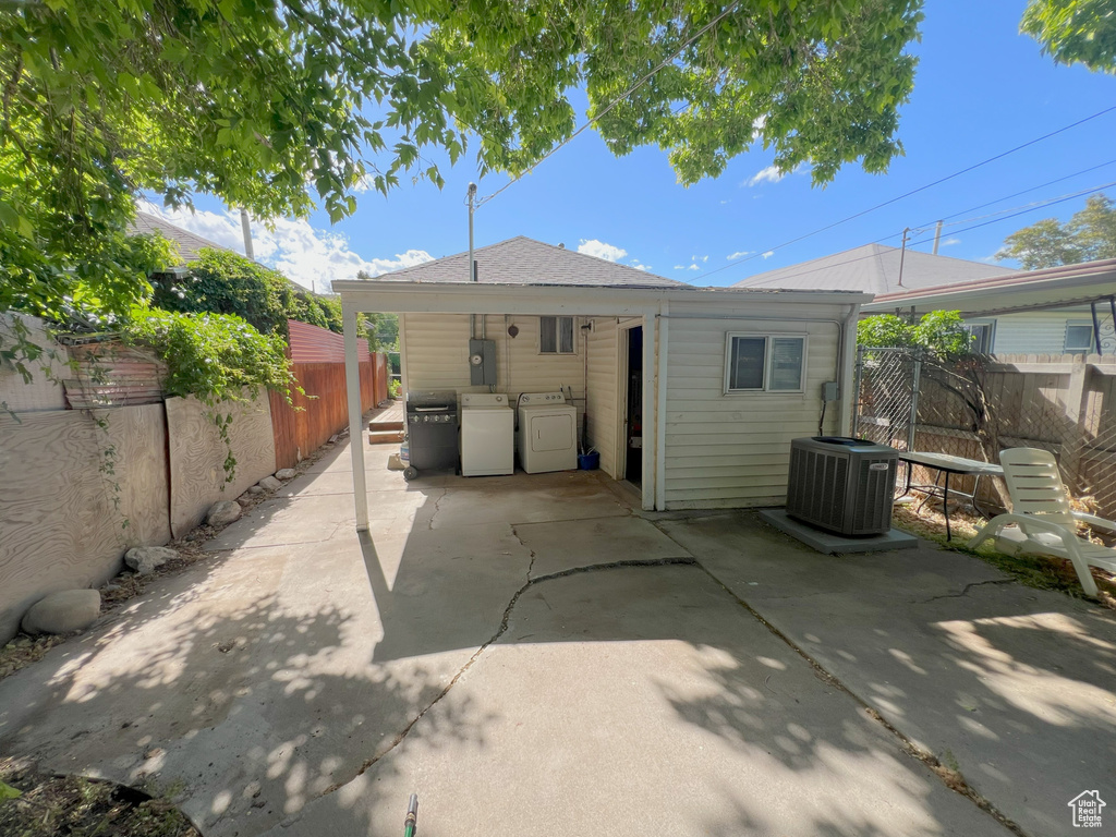 Rear view of property with a fenced backyard, central air condition unit, an outdoor kitchen, a patio, and washing machine and clothes dryer