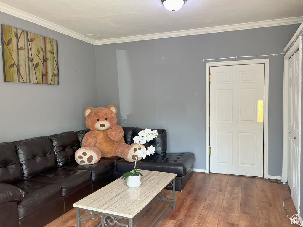Living area featuring wood finished floors, crown molding, and baseboards