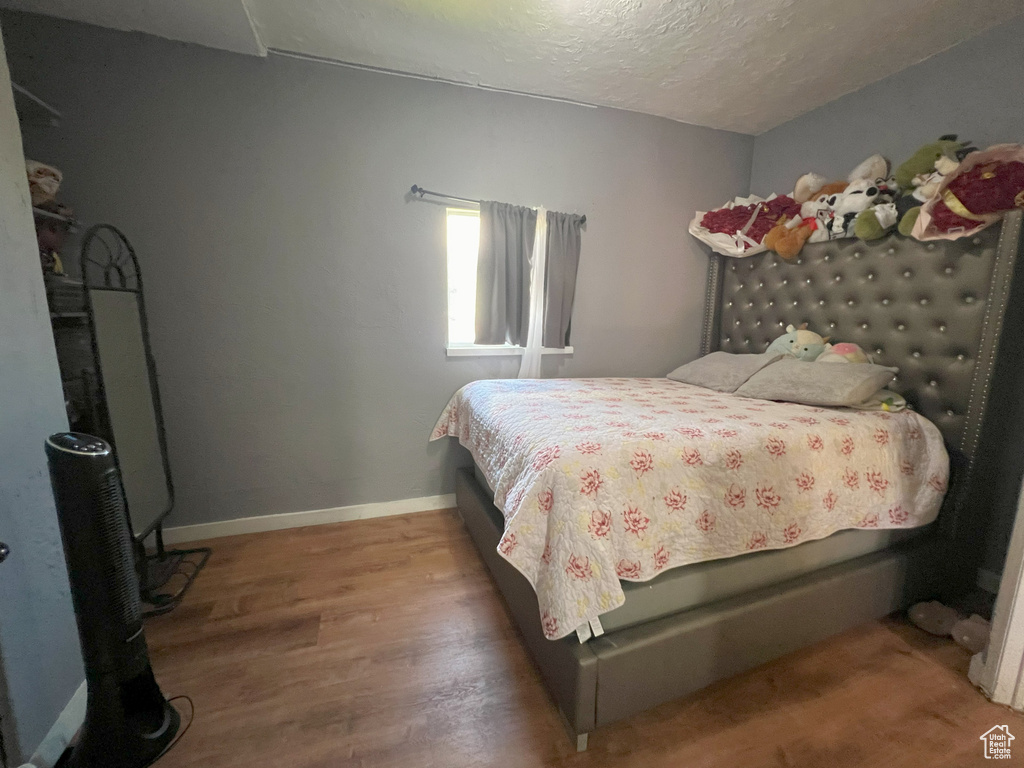 Bedroom with a textured ceiling, wood finished floors, and baseboards