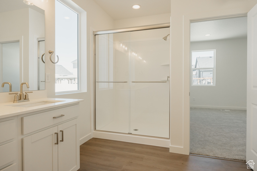 Full bath featuring vanity, a shower stall, wood finished floors, and recessed lighting
