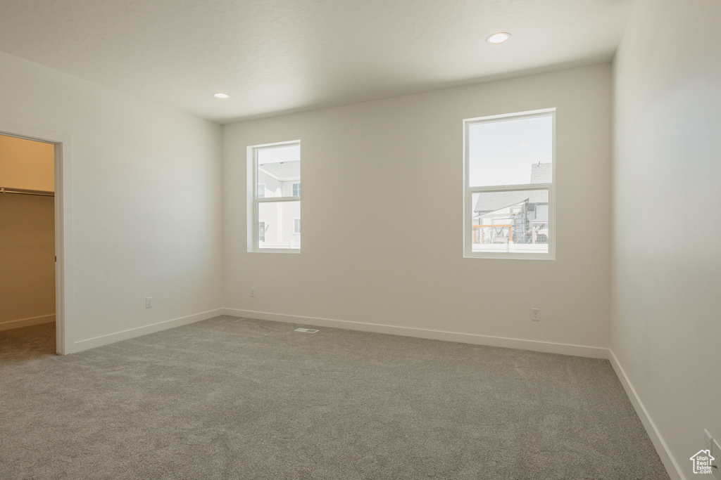 Unfurnished bedroom with a walk in closet, carpet floors, baseboards, and recessed lighting