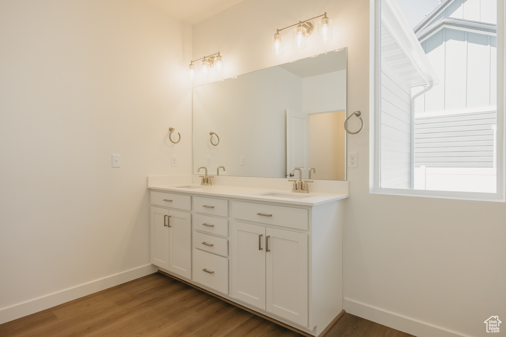 Full bathroom with plenty of natural light, double vanity, wood finished floors, and baseboards